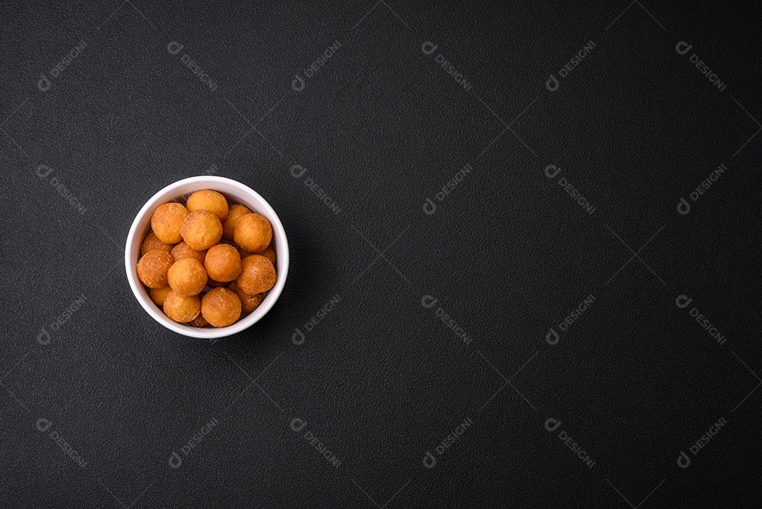Deliciosas bolas de batata frita com mussarela à milanesa, sal, especiarias e ervas sobre um fundo escuro de concreto