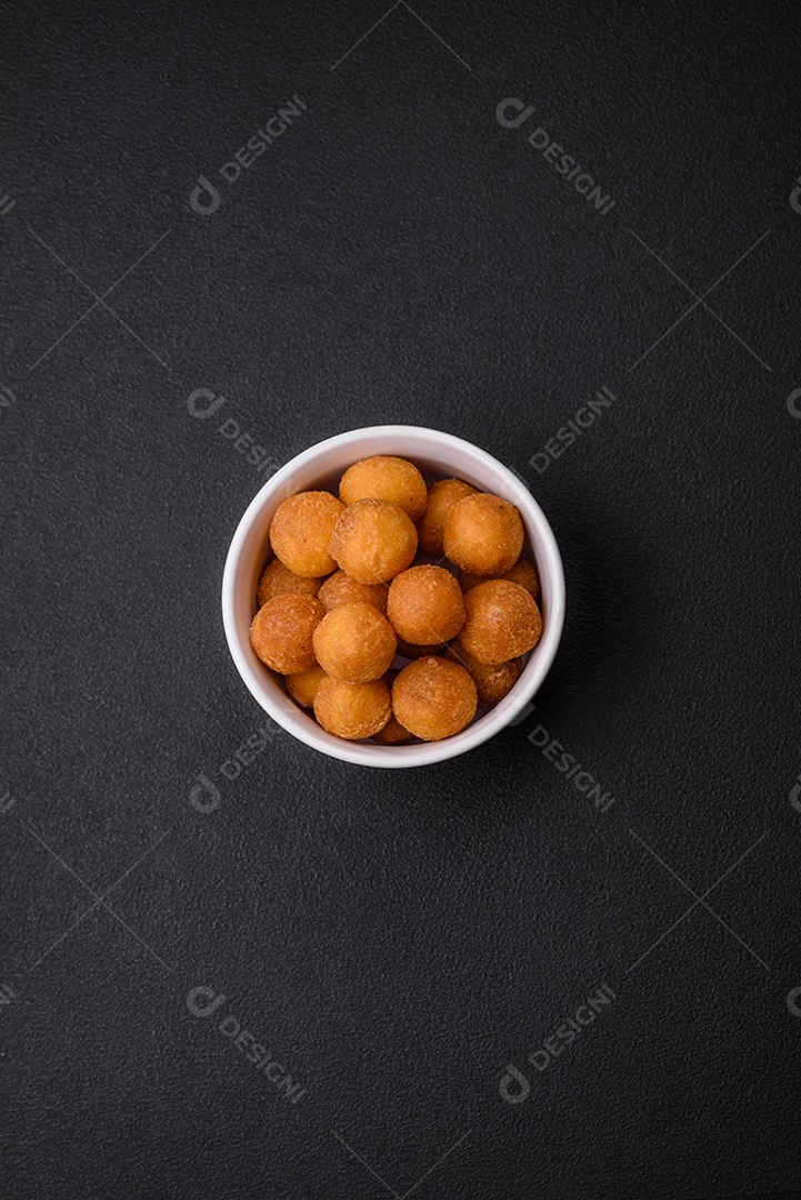 Deliciosas bolas de batata frita com mussarela à milanesa, sal, especiarias e ervas sobre um fundo escuro de concreto