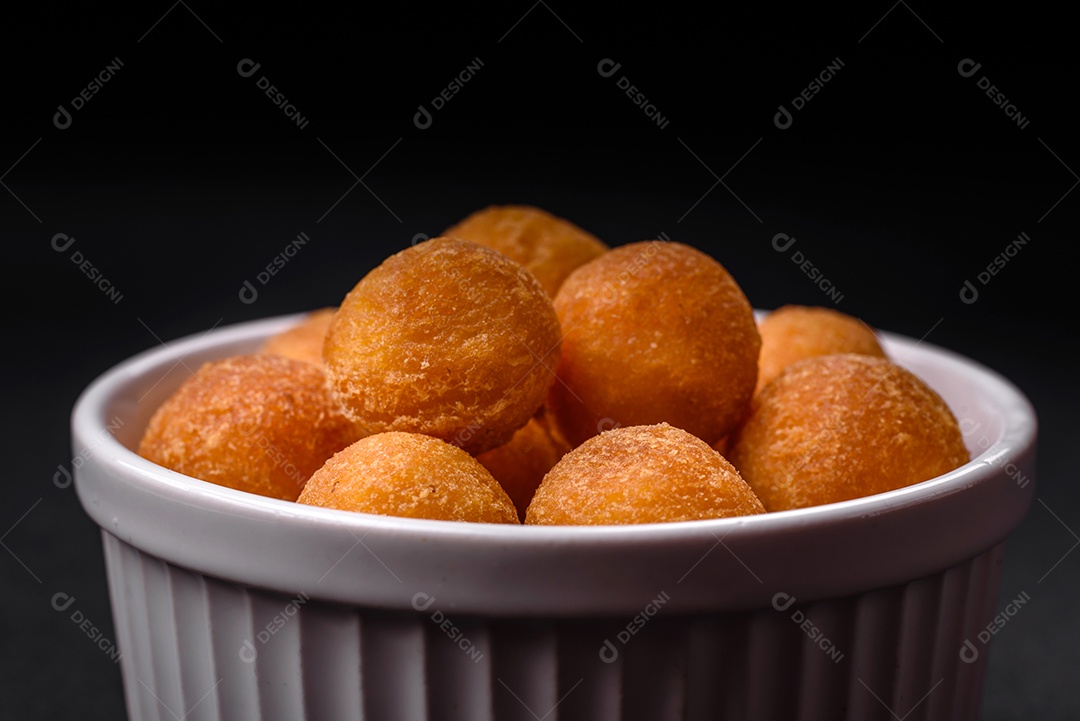 Deliciosas bolas de batata frita com mussarela à milanesa, sal, especiarias e ervas sobre um fundo escuro de concreto