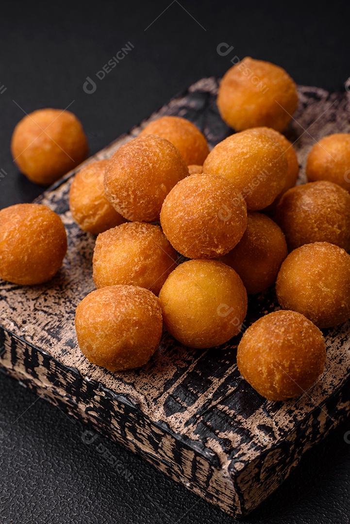 Deliciosas bolas de batata frita com mussarela à milanesa, sal, especiarias e ervas sobre um fundo escuro de concreto