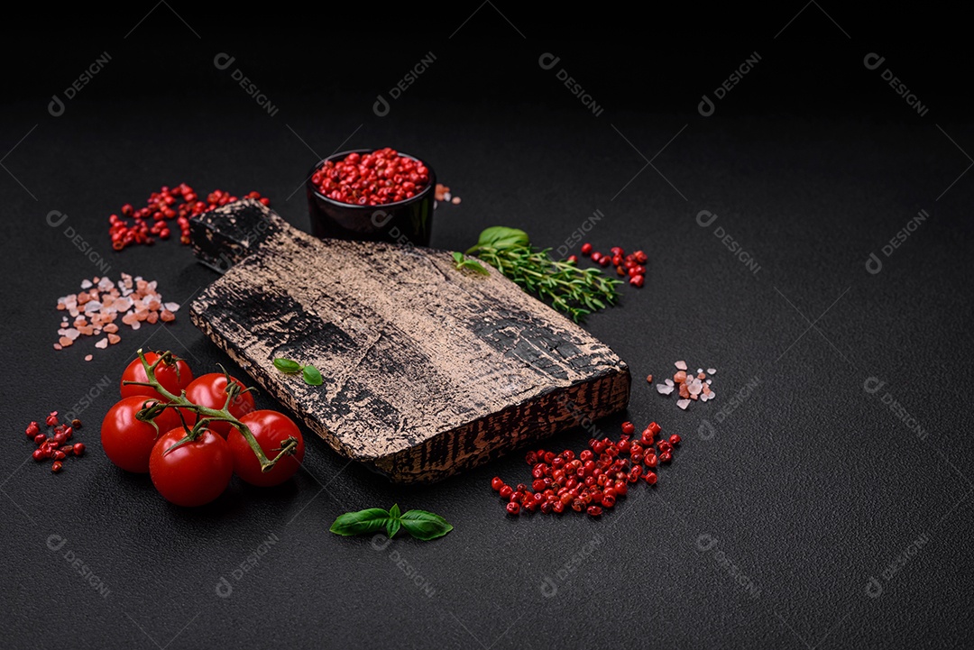 Ingredientes para cozinhar tomate cereja, sal, especiarias e ervas sobre um fundo escuro de concreto