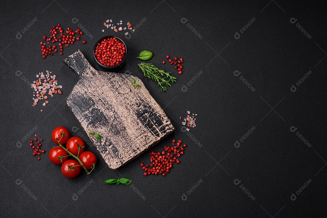 Ingredientes para cozinhar tomate cereja, sal, especiarias e ervas sobre um fundo escuro de concreto