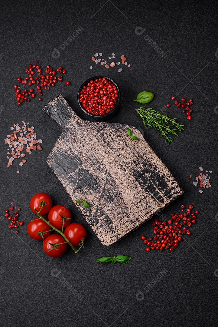 Ingredientes para cozinhar tomate cereja, sal, especiarias e ervas sobre um fundo escuro de concreto