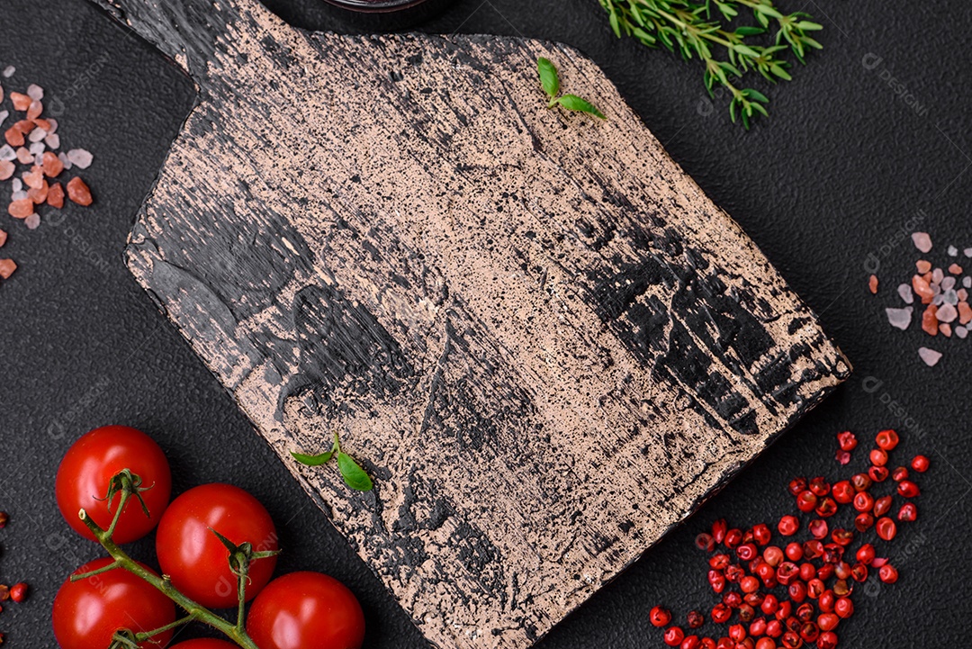 Ingredientes para cozinhar tomate cereja, sal, especiarias e ervas sobre um fundo escuro de concreto