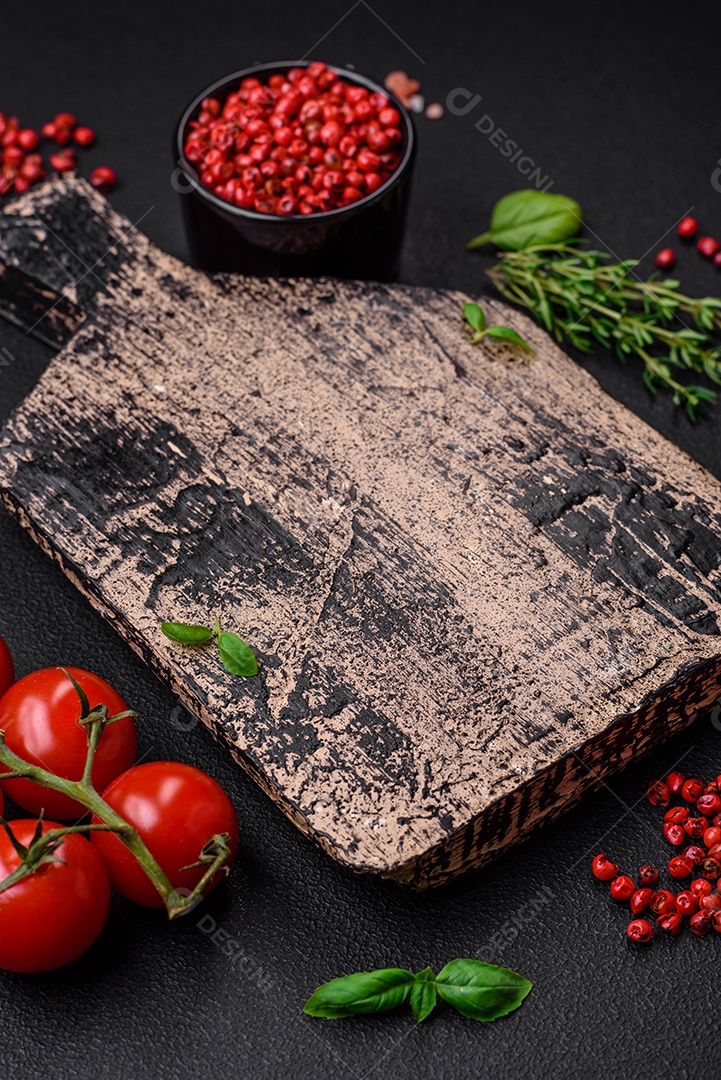 Ingredientes para cozinhar tomate cereja, sal, especiarias e ervas sobre um fundo escuro de concreto