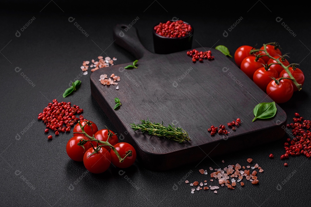 Ingredientes para cozinhar tomate cereja, sal, especiarias e ervas sobre um fundo escuro de concreto