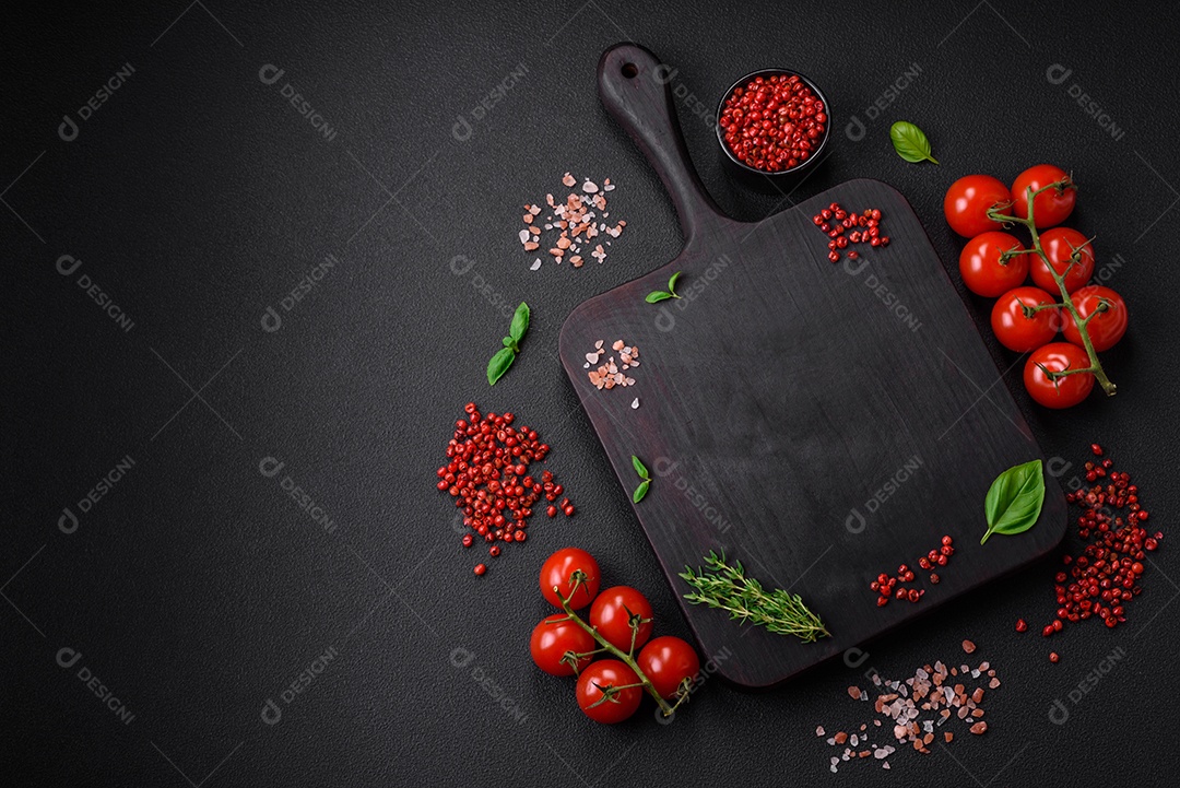 Ingredientes para cozinhar tomate cereja, sal, especiarias e ervas sobre um fundo escuro de concreto