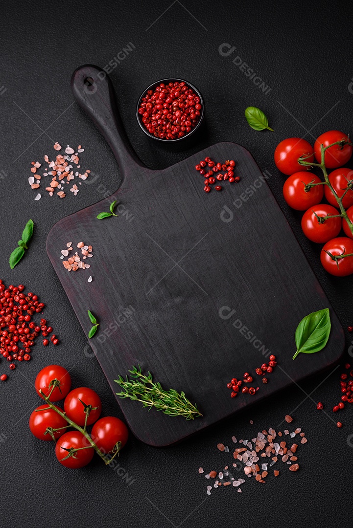 Ingredientes para cozinhar tomate cereja, sal, especiarias e ervas sobre um fundo escuro de concreto