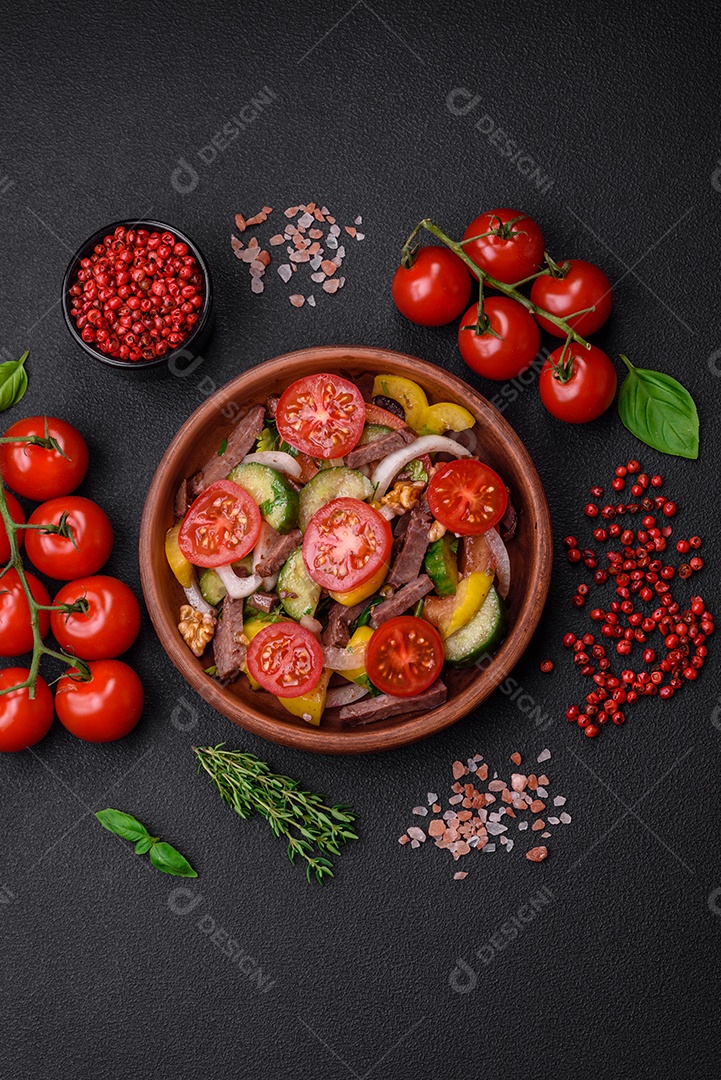 Deliciosa salada fresca com fatias de carne, tomate cereja, pimentão, sal, especiarias e ervas sobre um fundo de concreto texturizado
