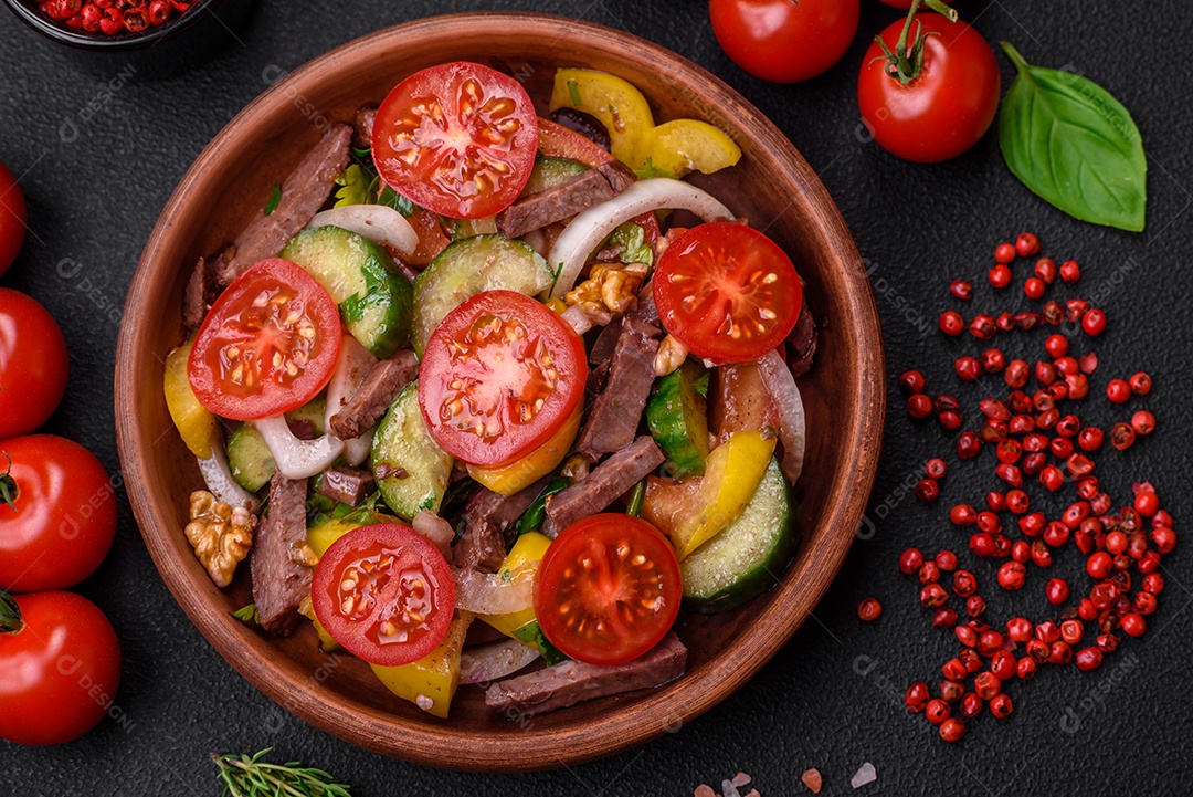 Deliciosa salada fresca com fatias de carne, tomate cereja, pimentão, sal, especiarias e ervas sobre um fundo de concreto texturizado
