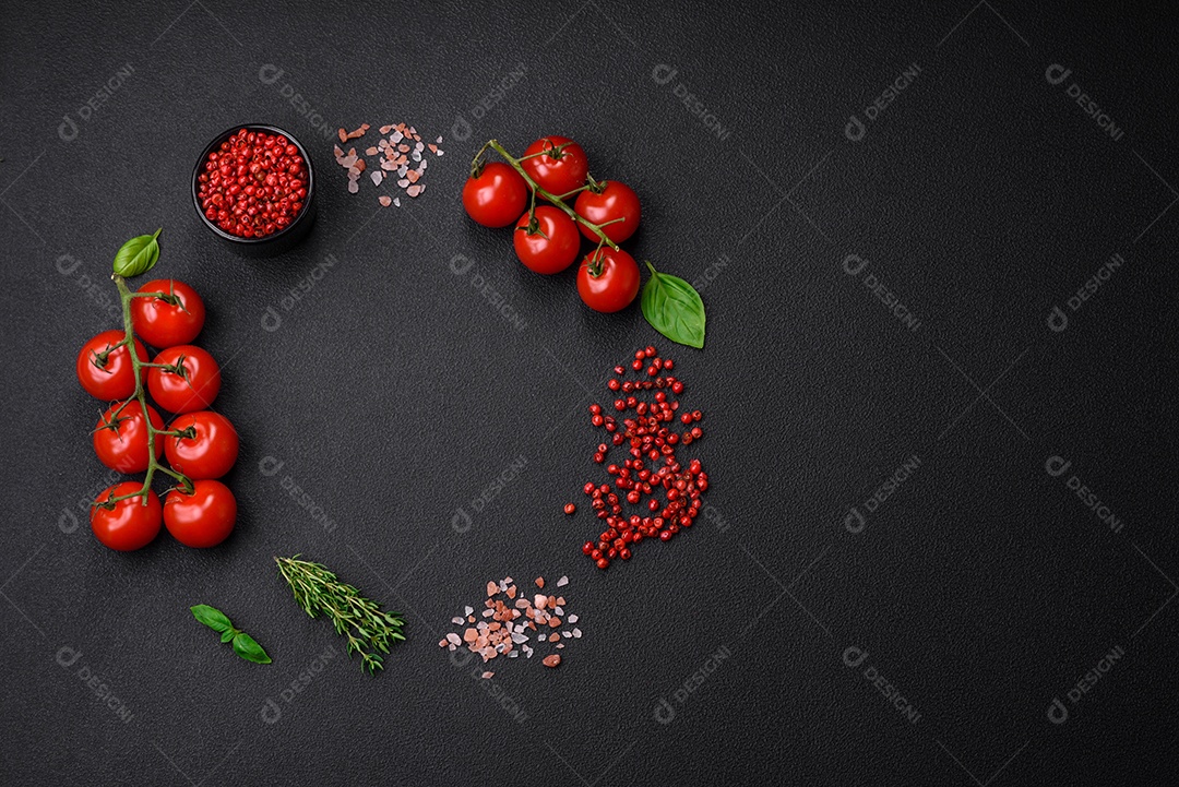 Ingredientes para cozinhar tomate cereja, sal, especiarias e ervas sobre um fundo escuro de concreto
