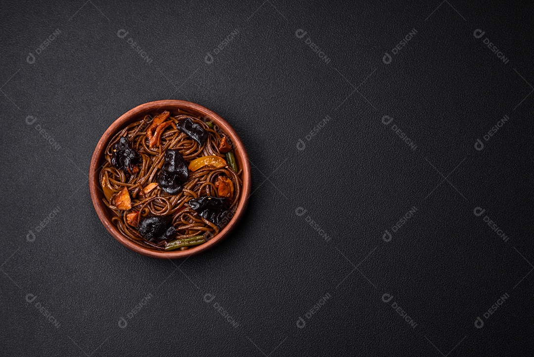 Delicioso macarrão de trigo sarraceno fresco ou udon com cogumelos, pimentões e outros vegetais, especiarias e ervas sobre um fundo escuro de concreto