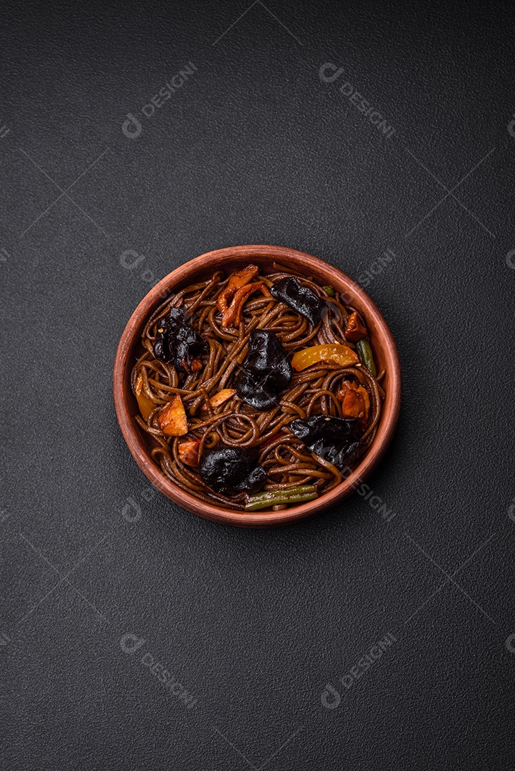 Delicioso macarrão de trigo sarraceno fresco ou udon com cogumelos, pimentões e outros vegetais, especiarias e ervas sobre um fundo escuro de concreto