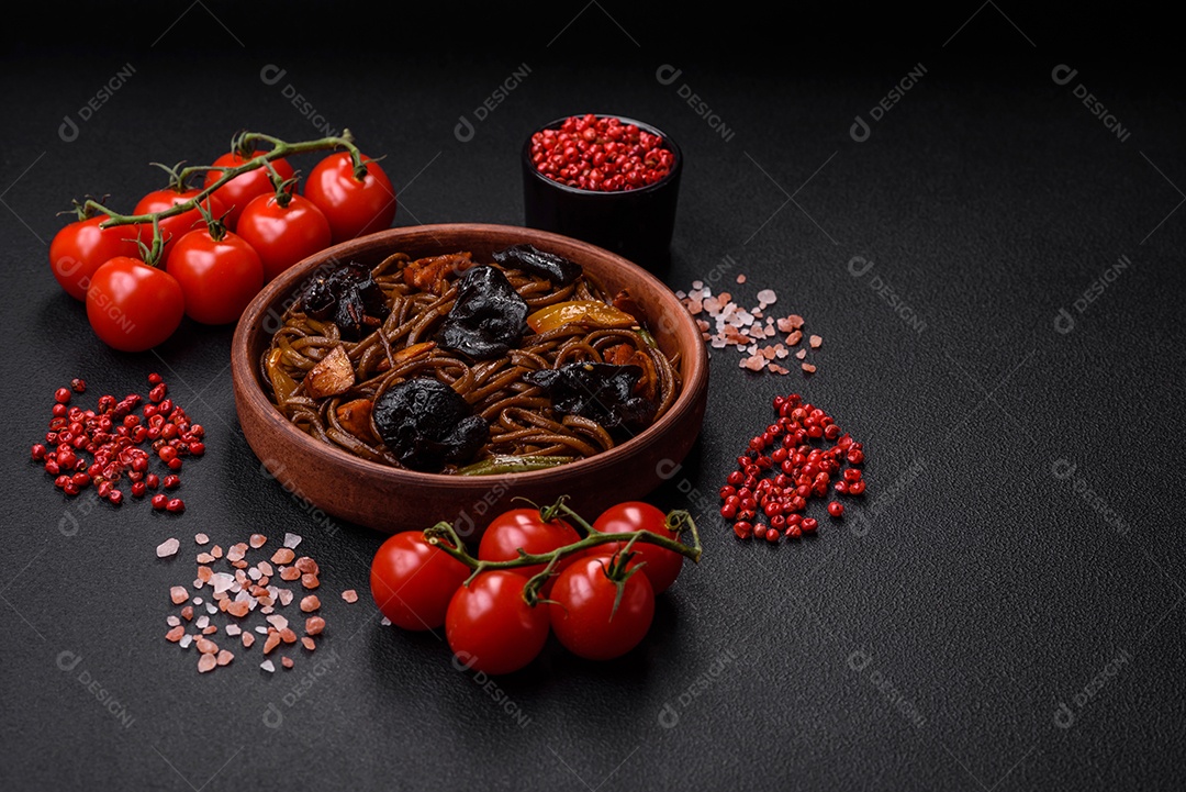 Delicioso macarrão de trigo sarraceno fresco ou udon com cogumelos, pimentões e outros vegetais, especiarias e ervas sobre um fundo escuro de concreto