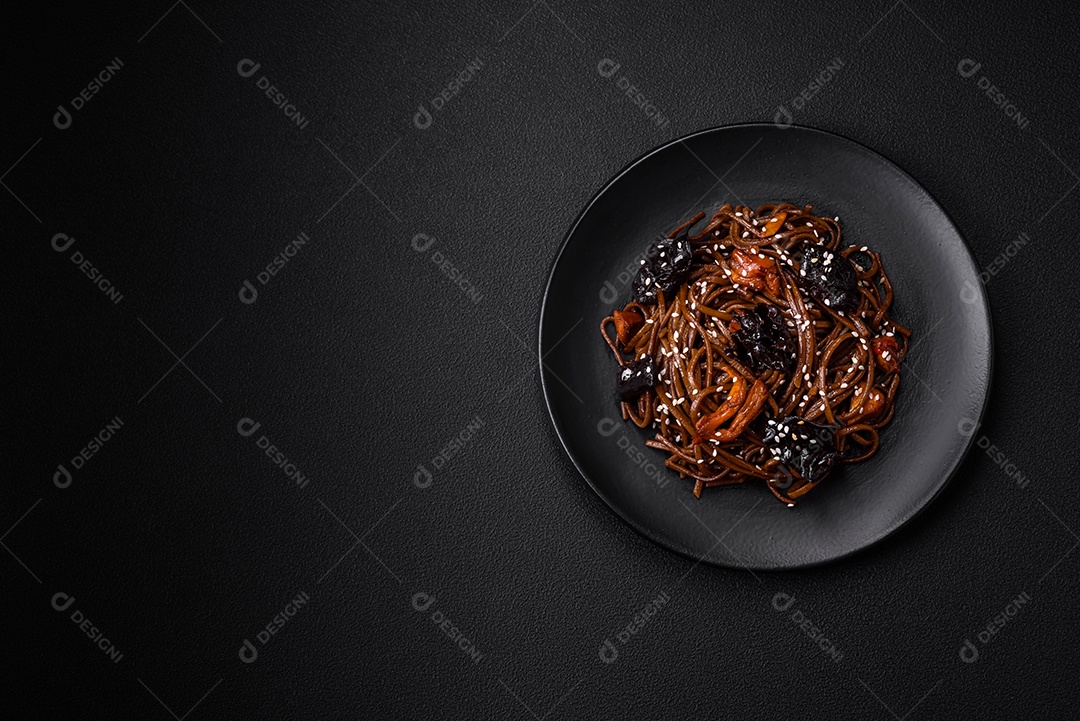 Delicioso macarrão de trigo sarraceno fresco ou udon com cogumelos, pimentões e outros vegetais, especiarias e ervas sobre um fundo escuro de concreto