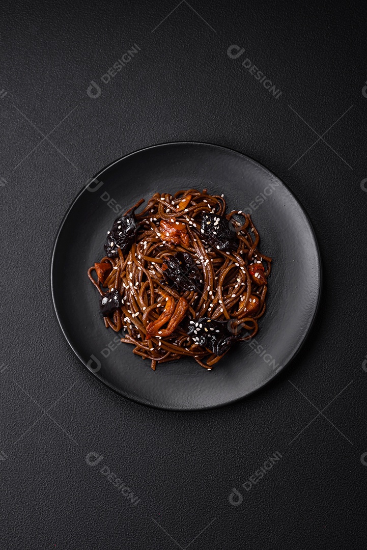 Delicioso macarrão de trigo sarraceno fresco ou udon com cogumelos, pimentões e outros vegetais, especiarias e ervas sobre um fundo escuro de concreto