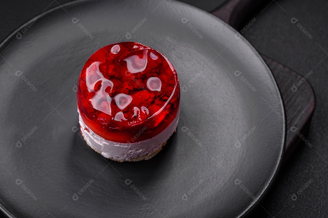 Delicioso bolo de queijo doce fresco com frutas e geleia de cor vermelha sobre um fundo escuro de concreto