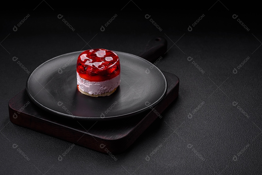 Delicioso bolo de queijo doce fresco com frutas e geleia de cor vermelha sobre um fundo escuro de concreto