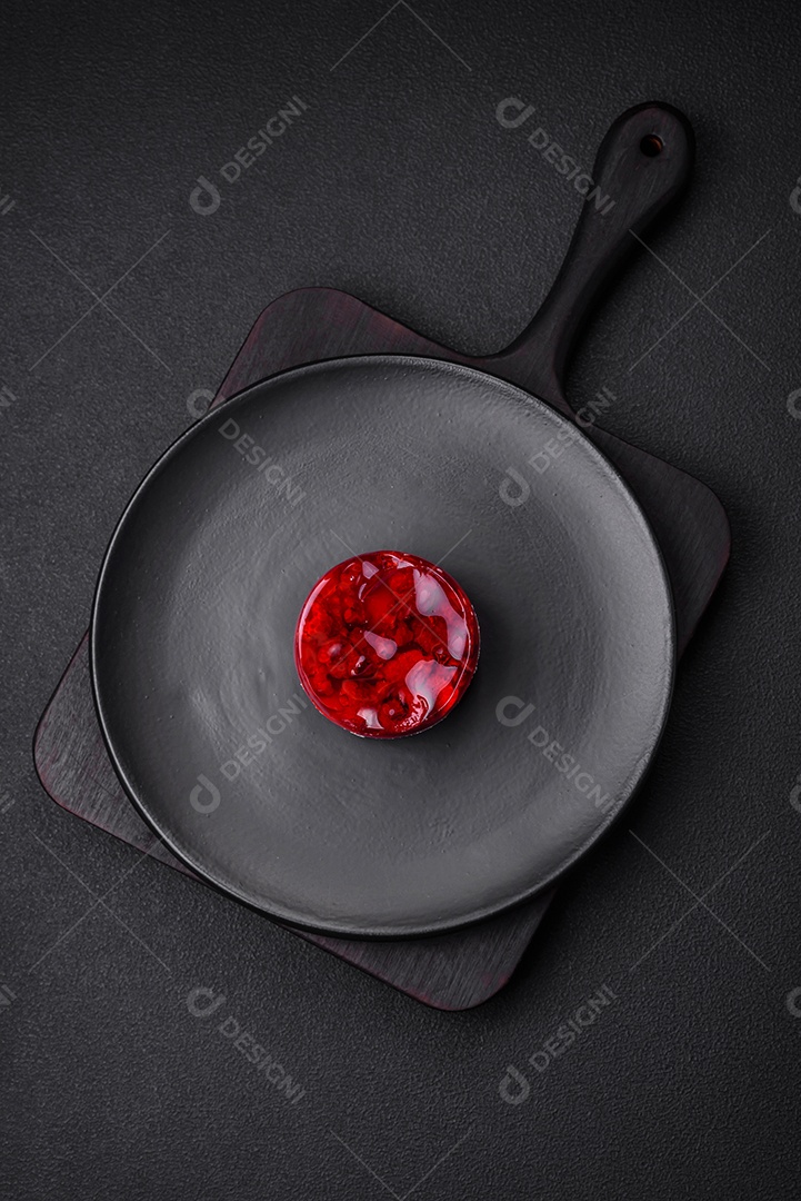 Delicioso bolo de queijo doce fresco com frutas e geleia de cor vermelha sobre um fundo escuro de concreto