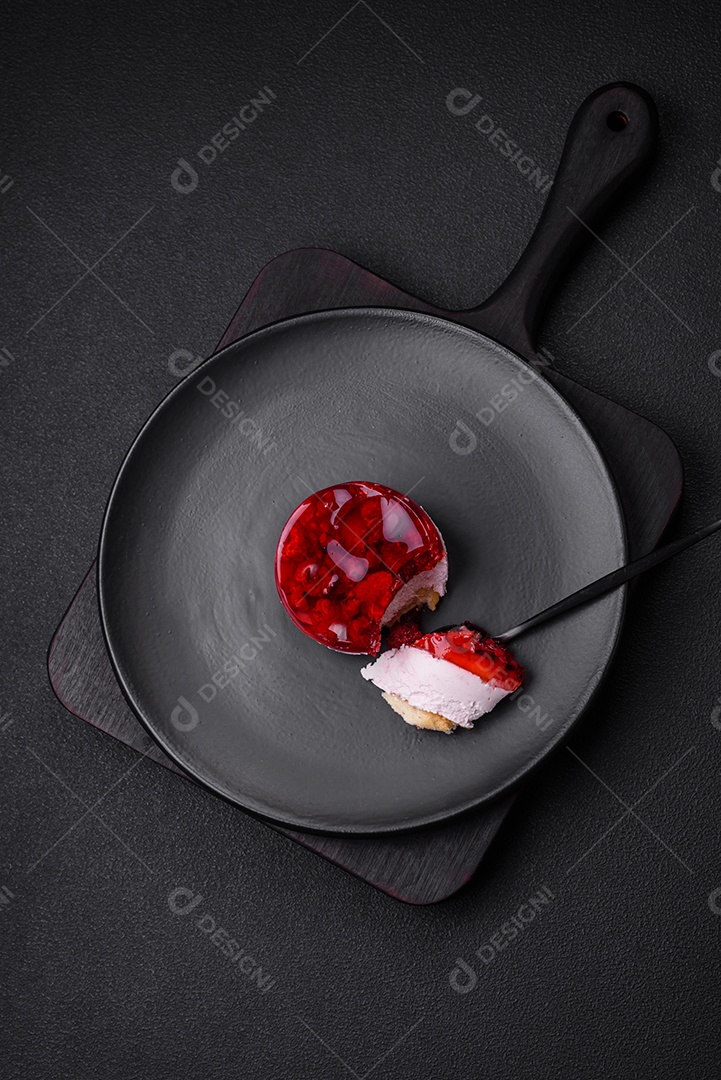 Delicioso bolo de queijo doce fresco com frutas e geleia de cor vermelha sobre um fundo escuro de concreto