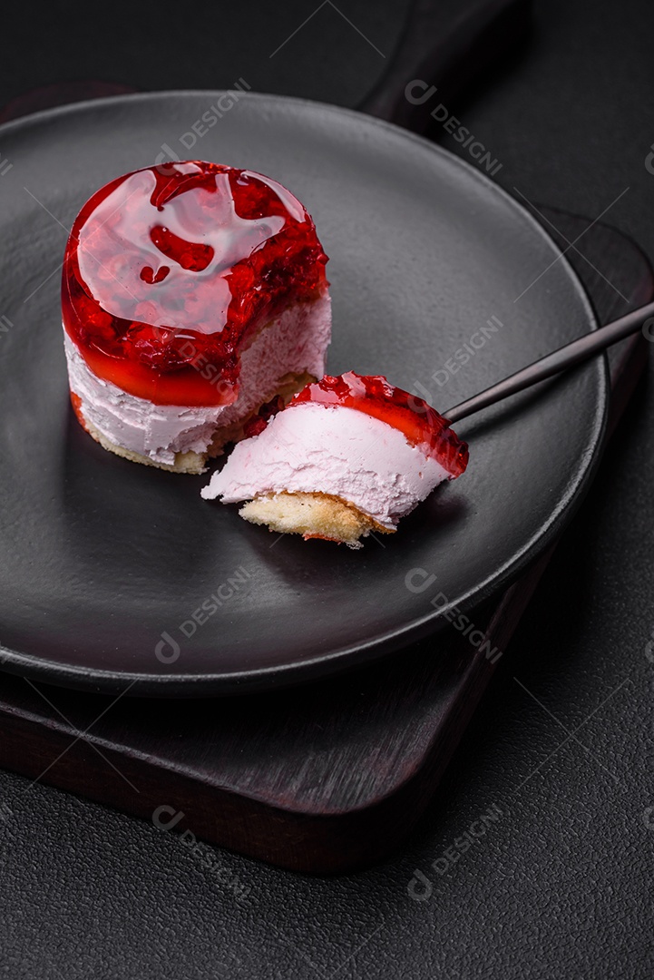 Delicioso bolo de queijo doce fresco com frutas e geleia de cor vermelha sobre um fundo escuro de concreto