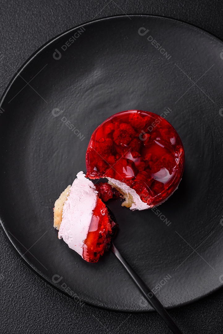 Delicioso bolo de queijo doce fresco com frutas e geleia de cor vermelha sobre um fundo escuro de concreto