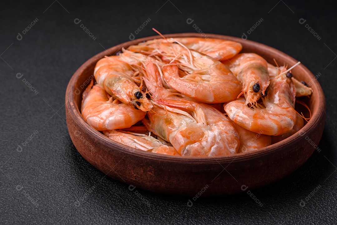 Deliciosos camarões tigre cozidos frescos com sal e especiarias numa placa cerâmica sobre um fundo escuro de concreto