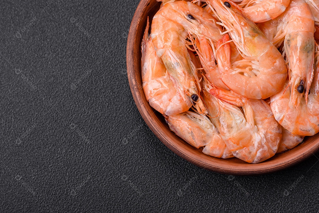 Deliciosos camarões tigre cozidos frescos com sal e especiarias numa placa cerâmica sobre um fundo escuro de concreto