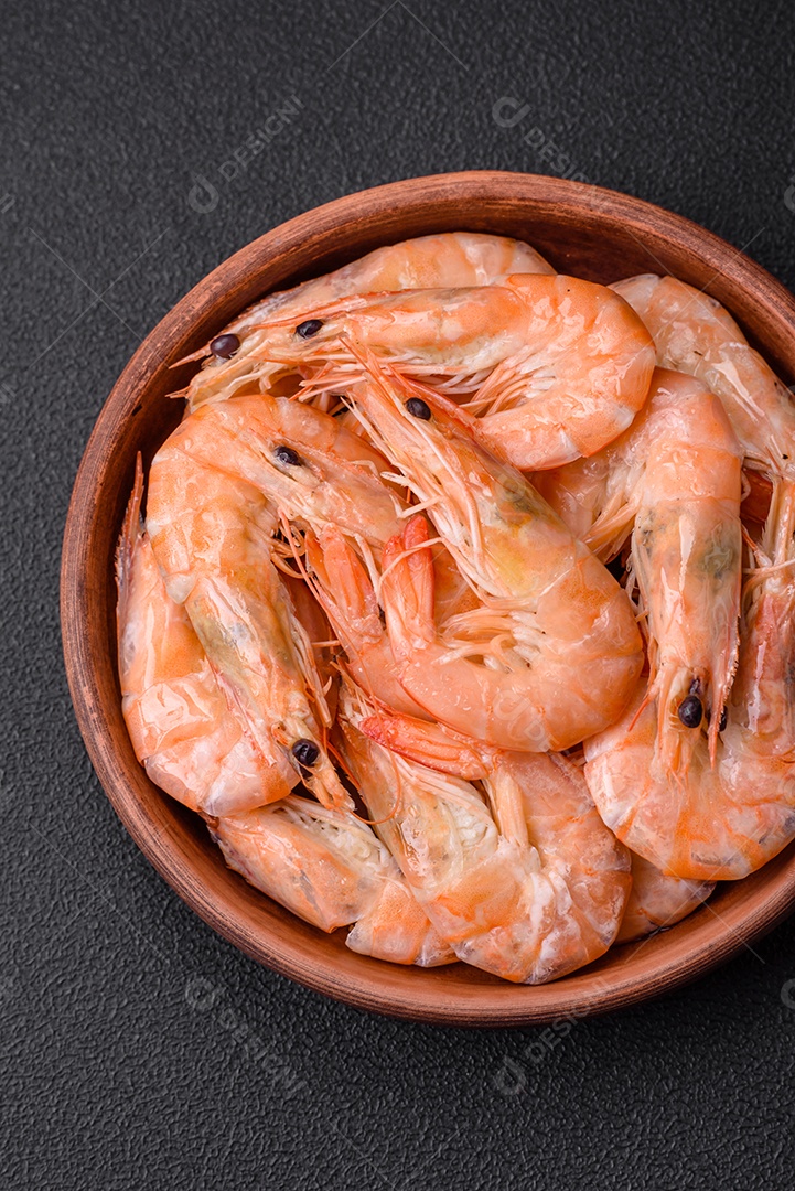 Deliciosos camarões tigre cozidos frescos com sal e especiarias numa placa cerâmica sobre um fundo escuro de concreto