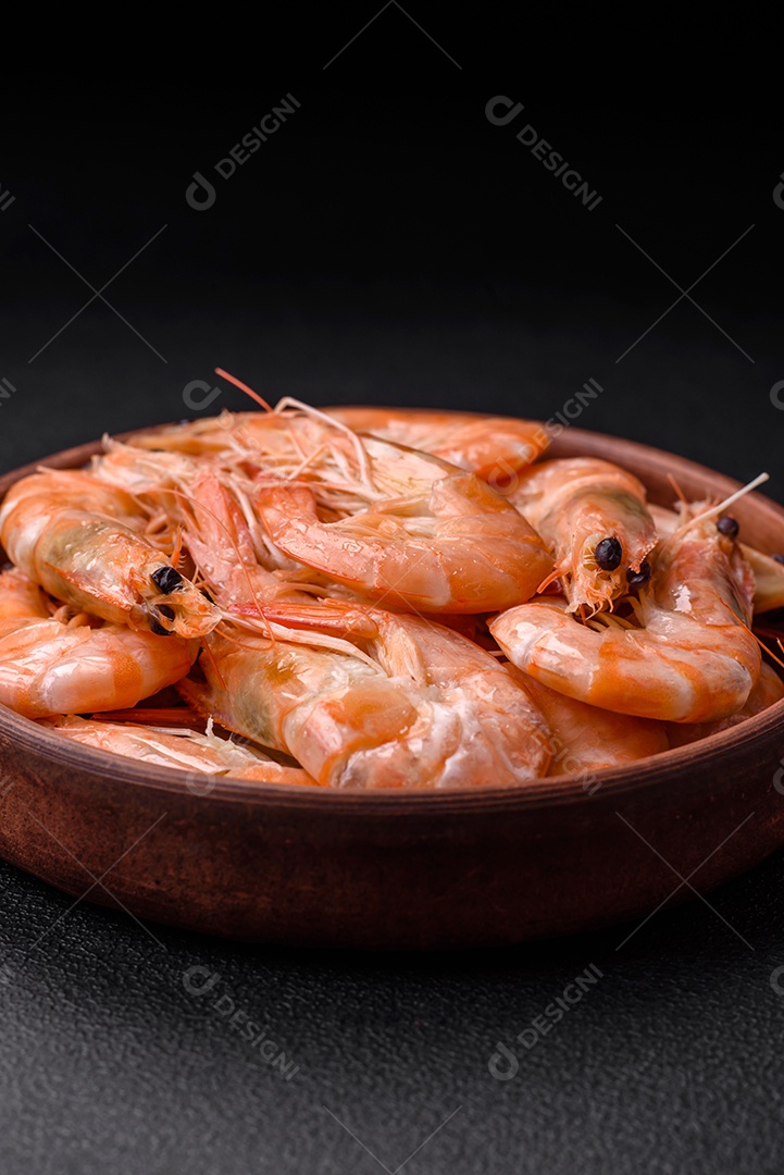 Deliciosos camarões tigre cozidos frescos com sal e especiarias numa placa cerâmica sobre um fundo escuro de concreto