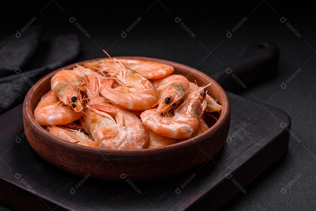 Deliciosos camarões tigre cozidos frescos com sal e especiarias numa placa cerâmica sobre um fundo escuro de concreto