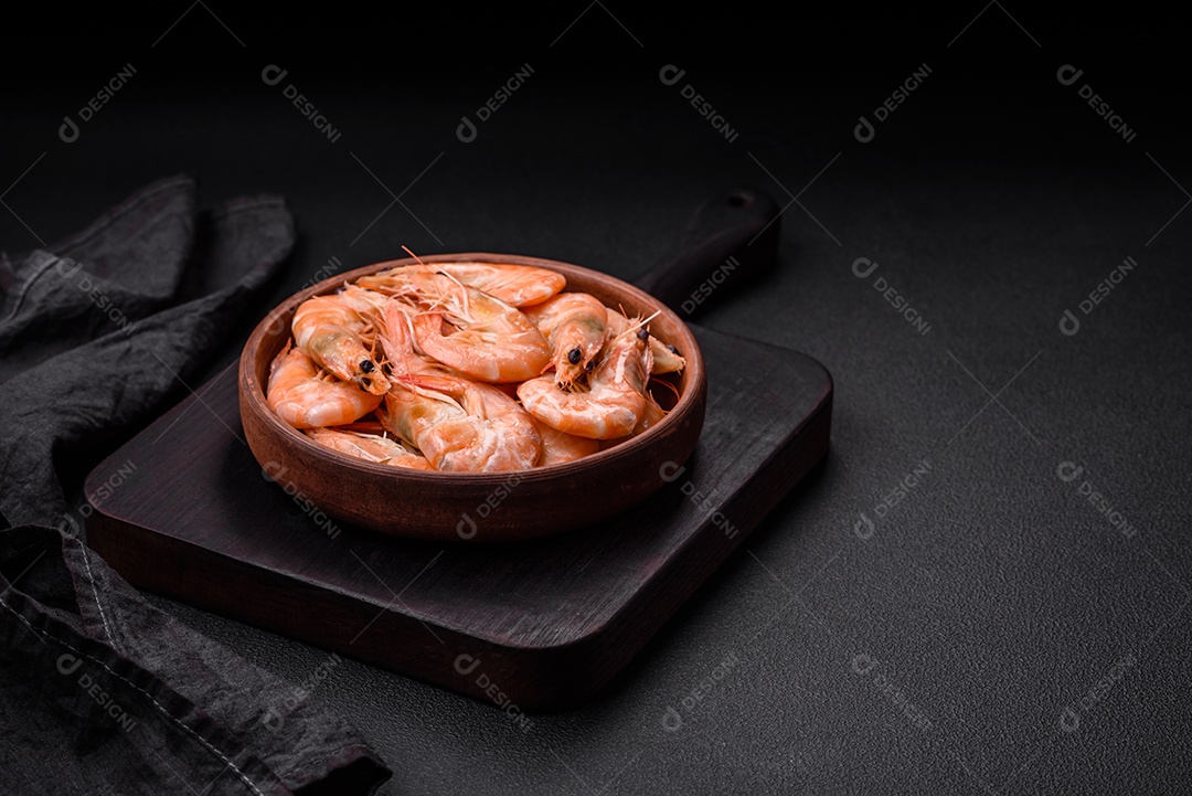 Deliciosos camarões tigre cozidos frescos com sal e especiarias numa placa cerâmica sobre um fundo escuro de concreto