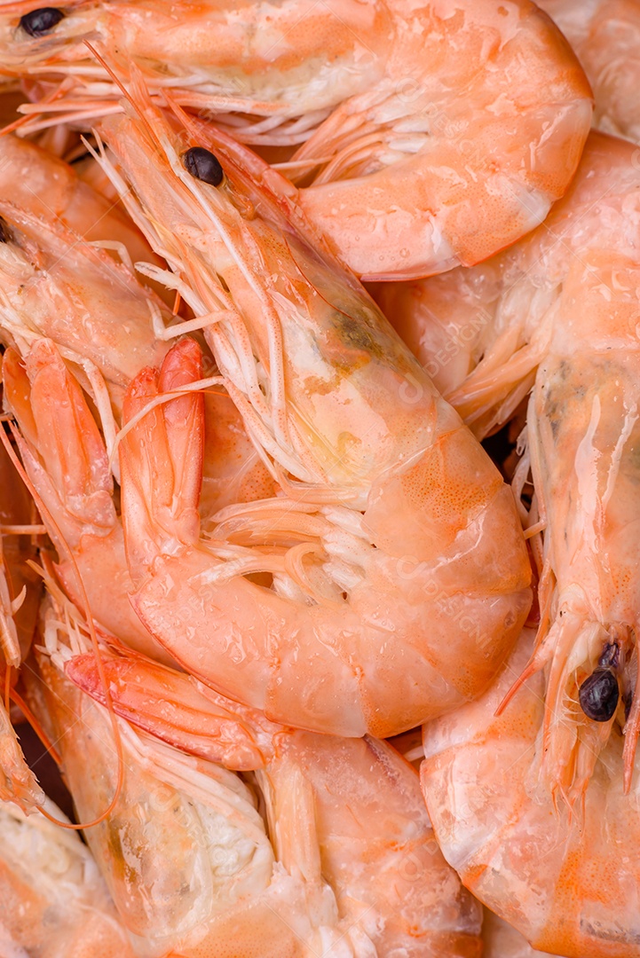 Deliciosos camarões tigre cozidos frescos com sal e especiarias numa placa cerâmica sobre um fundo escuro de concreto