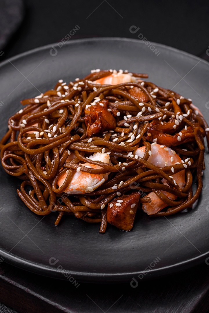 Delicioso macarrão de trigo sarraceno fresco ou udon com cogumelos, pimentões e outros vegetais, especiarias e ervas sobre um fundo escuro de concreto