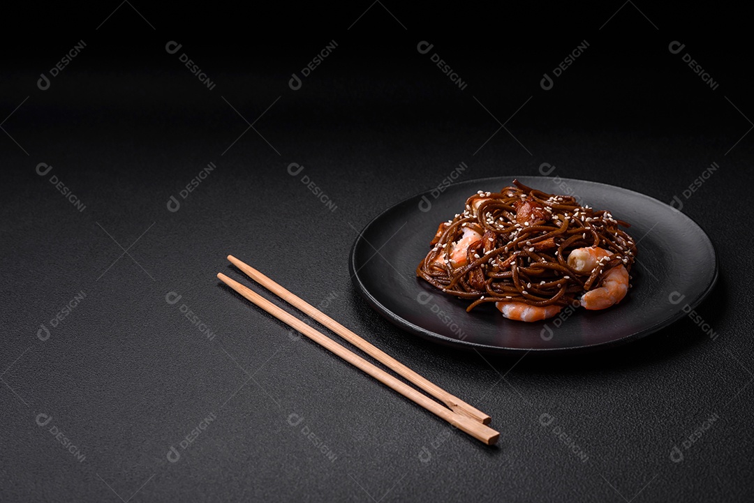 Delicioso macarrão de trigo sarraceno fresco ou udon com cogumelos, pimentões e outros vegetais, especiarias e ervas sobre um fundo escuro de concreto