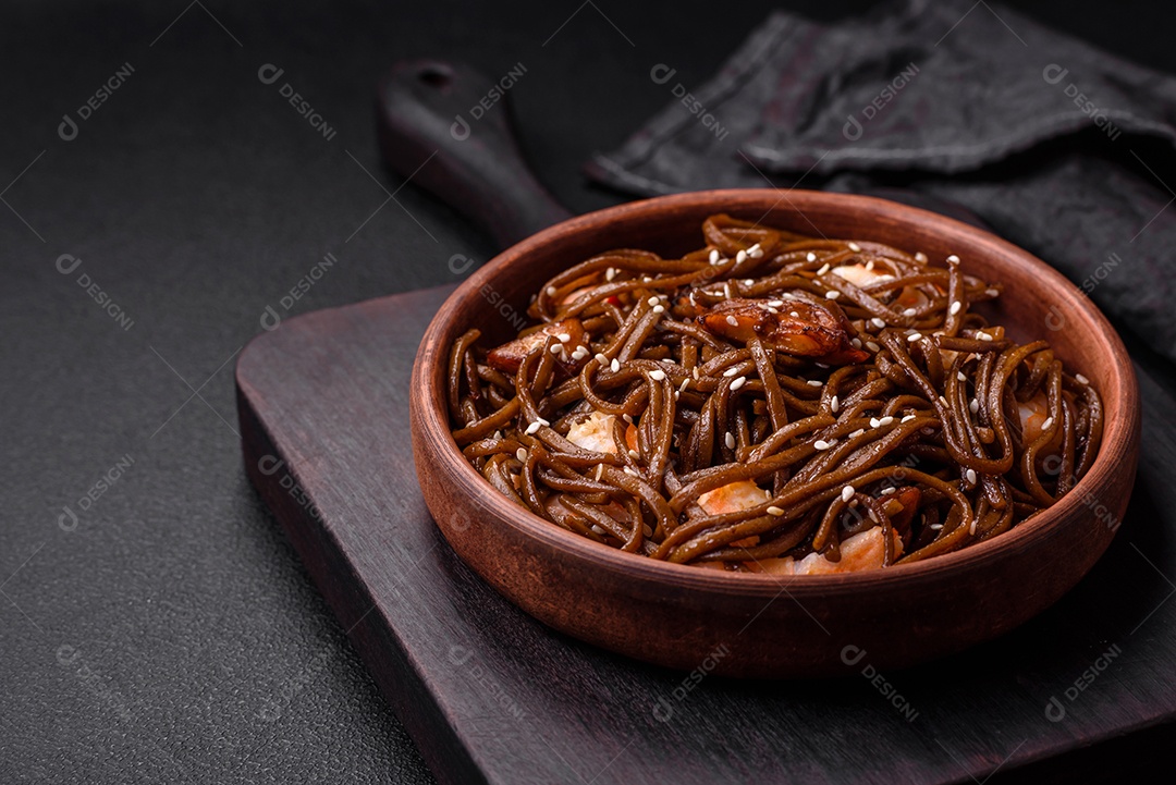 Delicioso macarrão de trigo sarraceno fresco ou udon com cogumelos, pimentões e outros vegetais, especiarias e ervas sobre um fundo escuro de concretoMacarrão massa comida alimento sobre tigela Fotos Imagem JPG