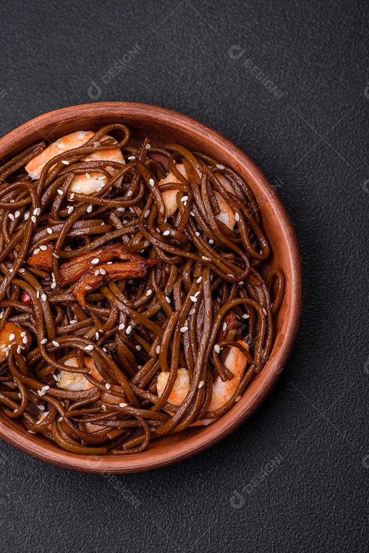 Delicioso macarrão de trigo sarraceno fresco ou udon com cogumelos, pimentões e outros vegetais, especiarias e ervas sobre um fundo escuro de concreto