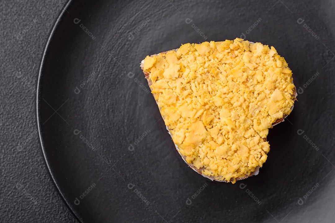 Deliciosa salada de mimosa fresca com conservas de peixe, ovo, moinese, queijo, sal e especiarias sobre fundo escuro de concreto