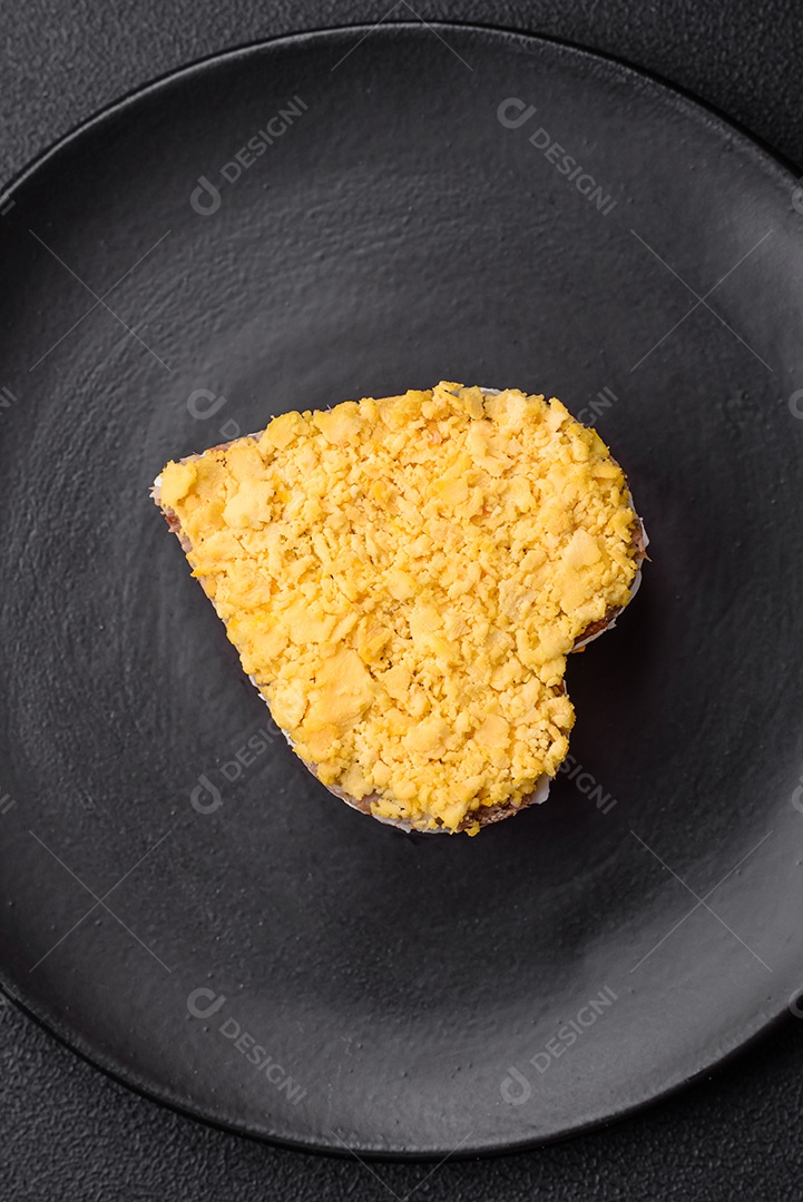 Deliciosa salada de mimosa fresca com conservas de peixe, ovo, moinese, queijo, sal e especiarias sobre fundo escuro de concreto