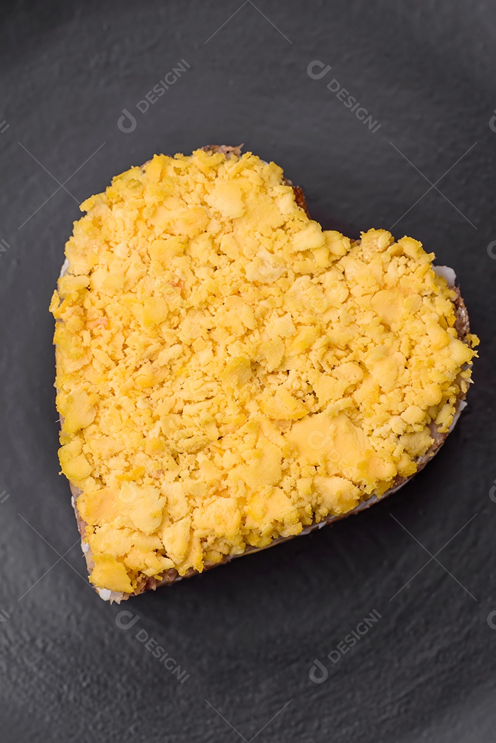 Deliciosa salada de mimosa fresca com conservas de peixe, ovo, moinese, queijo, sal e especiarias sobre fundo escuro de concreto