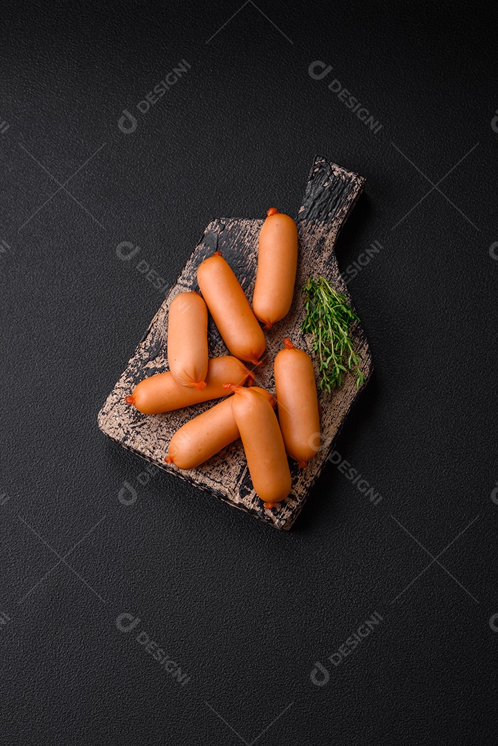 Deliciosas salsichas frescas cozidas com sal, especiarias e ervas sobre um fundo escuro de concreto