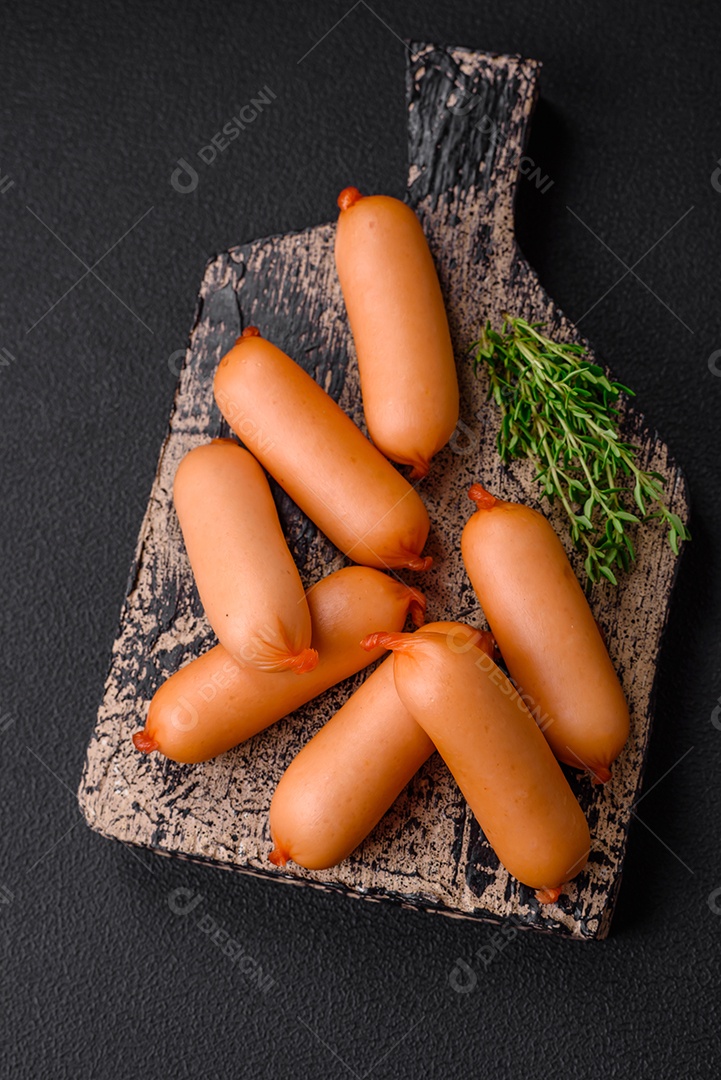 Deliciosas salsichas frescas cozidas com sal, especiarias e ervas sobre um fundo escuro de concreto