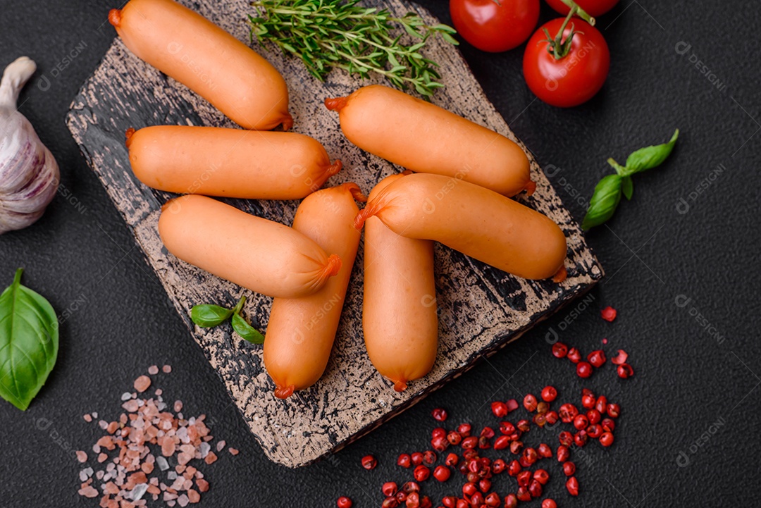 Deliciosas salsichas frescas cozidas com sal, especiarias e ervas sobre um fundo escuro de concreto