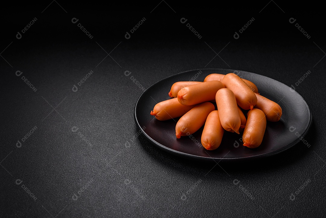 Deliciosas salsichas frescas cozidas com sal, especiarias e ervas sobre um fundo escuro de concreto