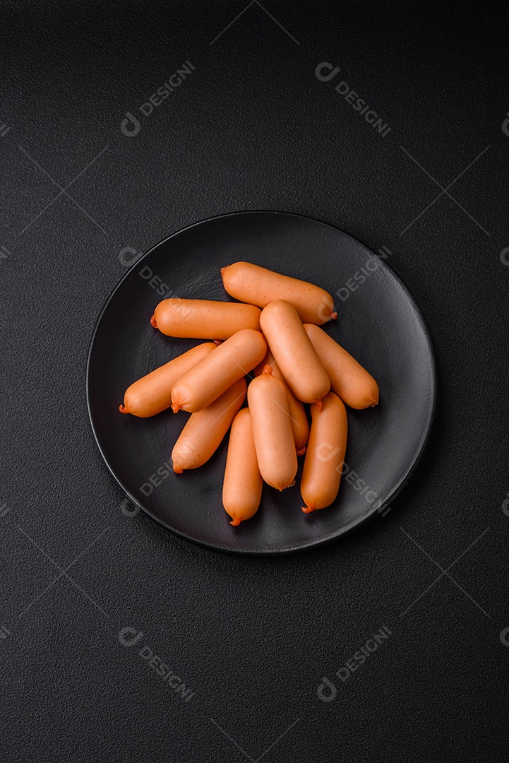 Deliciosas salsichas frescas cozidas com sal, especiarias e ervas sobre um fundo escuro de concreto