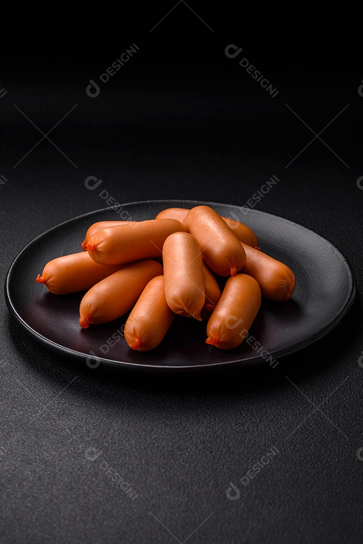 Deliciosas salsichas frescas cozidas com sal, especiarias e ervas sobre um fundo escuro de concreto