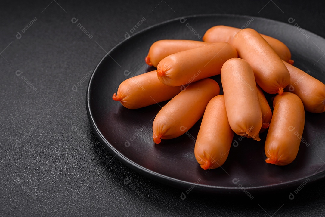 Deliciosas salsichas frescas cozidas com sal, especiarias e ervas sobre um fundo escuro de concreto