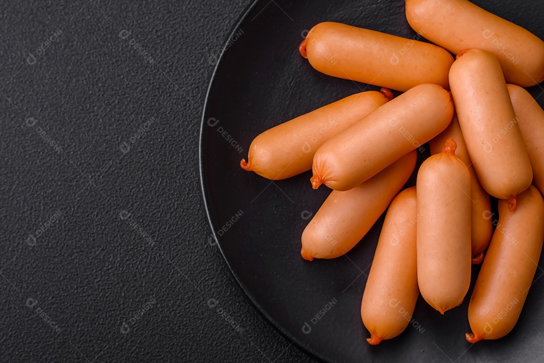 Deliciosas salsichas frescas cozidas com sal, especiarias e ervas sobre um fundo escuro de concreto