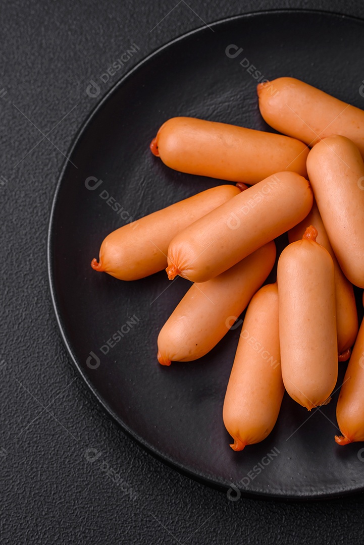 Deliciosas salsichas frescas cozidas com sal, especiarias e ervas sobre um fundo escuro de concreto