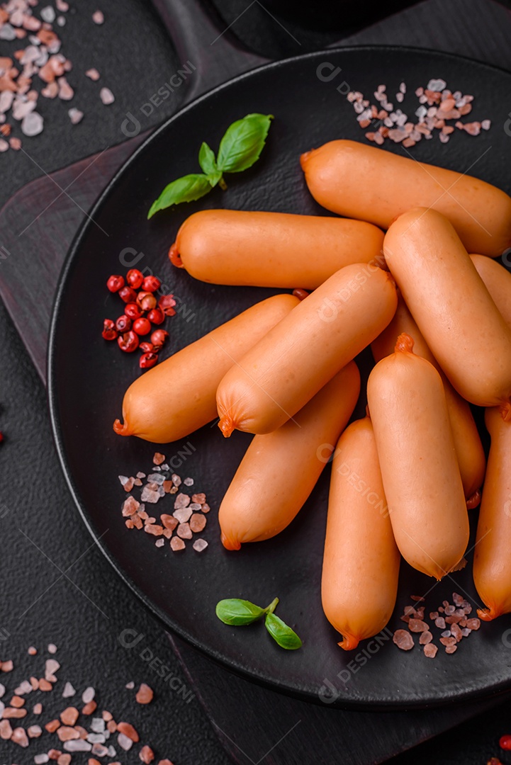 Deliciosas salsichas frescas cozidas com sal, especiarias e ervas sobre um fundo escuro de concreto